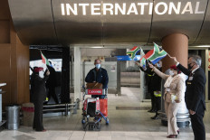 Passengers arrive to people waving flags and musicians playing music after flying on an Emirates flight from Dubai, one of the first international commercial flights coming into South Africa, at the Cape Town International airport in Cape Town on October 1, 2020. 
