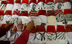 A batik producer creates cloth face masks in the red and white of the Indonesian flag in Kedungmundu, Semarang, Central Java, on July 24, 2020.