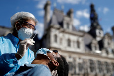 A health worker, wearing a protective suit and a face mask, prepares to administer a nasal swab to a patient at a testing site for the coronavirus disease (COVID-19) installed in front of the city hall in Paris, France, on September 2, 2020. 
