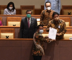 Coordinating Economic Minister Airlangga Hartarto (right) and Law and Human Rights Minister Yasonna Laoly (left) receive a final report from House of Representatives Legislation Body (Baleg) head Supratman Andi Atgas (below) during a plenary meeting to pass the omnibus bill on job creation into law at the House complex in Jakarta on Oct. 5.