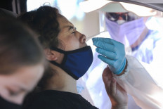 A healthcare worker assists a motorist with a nasal swab test at a drive-in coronavirus (COVID-19) testing center at M.T.O. Shahmaghsoudi School of Islamic Sufism on August 11, 2020 in Los Angeles, California. 