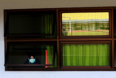 An asymptomatic COVID-19 patient looks out the window while undergoing isolation at the Patriot Candrabhaga Stadium isolation center in Bekasi, West Java on October. 2. 2020. The isolation ward at the stadium has the capacity to house 55 patients. JP/Dhoni Setiawan