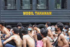 Police officers guard a group of shirtless protesters who were detained on Oct. 8, 2020, while taking part in demonstrations against the newly passed Job Creation Law in Central Jakarta.