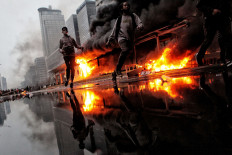 Up in flames: Protesters run past the Hotel Indonesia Transjakarta bus shelter in Central Jakarta as it is engulfed by a fire during a demonstration on Thursday, October 8. 2020 that turned violent. Nationwide demonstrations since Tuesday have demanded the immediate revocation of the Job Creation Law. JP/Seto Wardhana
