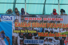 Putting their foot down: Members of a factory union stand behind a banner protesting the recently passed omnibus bill on job creation during a strike on Wednesday, October 7.2020 at the sports footwear factory of PT Panarub Industry in Tangerang. The banner calls on workers to answer to the “challenge”: “Don’t let them silence you. Reject and challenge the omnibus law on job creation.” JP/Dhoni Setiawan