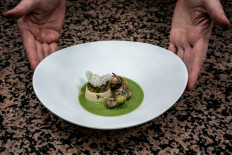 French chef Gilles Reinhardt shows a plate with frog legs in the restaurant of Paul Bocuse 'Auberge Du Pont de Collonges' in Collonges au Mont D'Or, near Lyon, central France, on October 8, 2020. 