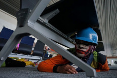 Emergency drill: An officer takes shelter under a bench during an emergency situation simulation held as part of the Indian Ocean Wave Exercise (IOWave) on Oct. 6 at Yogyakarta International Airport (YIA) in Kulon Progo regency, Yogyakarta. The event was organized by the Meteorology, Climatology and Geophysics Agency. 