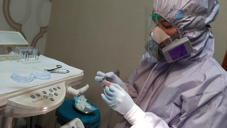 Really artificial: Dela, a dentist, examines an artificial tooth prior to being placed into a patient’s mouth.