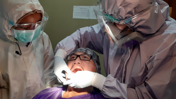 Open wide: Dela, a dentist (right) fixes a crown on a patient’s tooth in a dental clinic in Cipete, South Jakarta. During the procedure, Dela and her assistant have to wear personal protective equipment (PPE).  