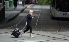A woman crosses a street in Melbourne on October 18, 2020, as the state government announces a lifting of some restrictions as the city battles a second wave of the Covid-19 coronavirus.