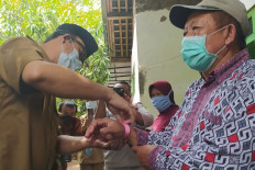 Banyumas Regent Achmad Husein puts a pink plastic bracelet on Edhi Ahmadi, 67, resident of Danaraja, Banyumas, East Java on Oct. 19, 2020. The Banyumas administration kick-started a pilot project dubbed Desa Jaga Komorbid, a derivative program of Central Java’s Jogo Tonggo (Taking Care of Neighbor) initiative. The project marks the elderly and people with comorbidities with pink plastic bracelets.