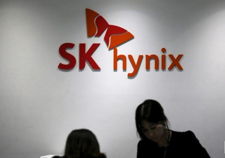 Employees talk in front of the logo of SK Hynix at its headquarters in Seongnam, South Korea, April 25, 2016. 