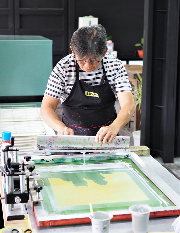 Capturing details: Devy Ferdianto, cofounder and head of Black Hand Gang printmaking studio, makes an original art print using hand pulled screenprinting techniques. 