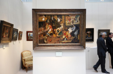 Visitors walk past a painting by Flemish painter Pieter Brueghel the Younger entitled 'L'Alchimiste' and displayed on an exhibition stand during the 26th edition of the 'Biennale des antiquaires' (the antique dealers biennial fair) on September 13, 2012 at the Grand Palais in Paris. 