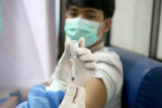 Test run: A medical professional at a community health center (Puskesmas) in Tapos, Depok, West Java, administers a vaccine during a COVID-19 vaccination simulation on Oct. 21, 2020. 