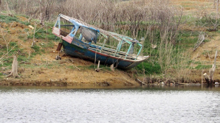 Grounded: A damaged wooden boat is stranded on the embankment of Southeast Asia's second-largest reservoir.