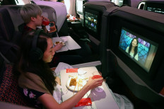 Diners watch movies while dining in business class during the inaugural lunch at Restaurant A380 @Changi onboard a Singapore Airlines Airbus A380 plane at Changi International Airport in Singapore on October 24, 2020.