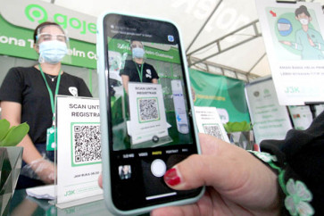 Staying safe: A commuter scans a code to leave her helmet at a Gojek comfort zone at Depok Baru railway station, Depok, West Java, on Monday. Gojek has expanded its healthy, clean and safe zones at several railway stations in greater Jakarta.