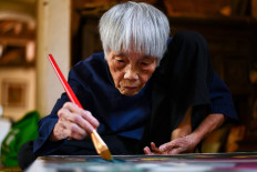 This photograph taken on October 8, 2020 shows 89-year-old Vietnamese artist Mong Bich painting at her house in Bac Ninh province, east of Hanoi. 