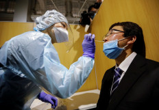 A medical worker wearing a protective suit conducts a simulation for a polymerase chain reaction (PCR) test at newly-opened Narita International Airport PCR Center operated by Nippon Medical School Foundation, a coronavirus disease (COVID-19) testing facility aimed at outbound travelers who need proof that they do not have the virus before arriving at their destination, at Narita International Airport in Narita, east of Tokyo, Japan, November 2, 2020. 