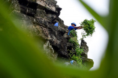 This photo taken on October 12, 2020 shows a gardener removing tree saplings from the exterior of the Angkor Wat temple in Siem Reap province. 