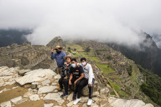 Tourists poses for a photo in front of the archaeological site of Machu Picchu, in Cusco, Peru on November 2, 2020, amid the new coronavirus pandemic. 