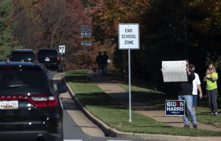 A man holds up a sign as the motorcade with US President Donald Trump drives past in Sterling, Virginia, on November 7, 2020.  (Agence France Presse/Andrew Cabellero-Reynolds).
Usage: 0