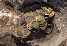 An Israeli worker unearthes gold coins dating to the Abbasid Caliphate, during a press presentation of the discovery at an archeological site near Tel Aviv in central Israel, on August 18, 2020. 