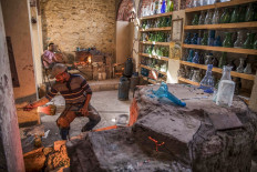 A glassblower sculpts a vessel at a workshop near the 15th century Sultan Qaitbay mosque complex in the 'Desert of the Mamluks' (City of the Dead) area of Egypt's capital Cairo on November 1, 2020. 