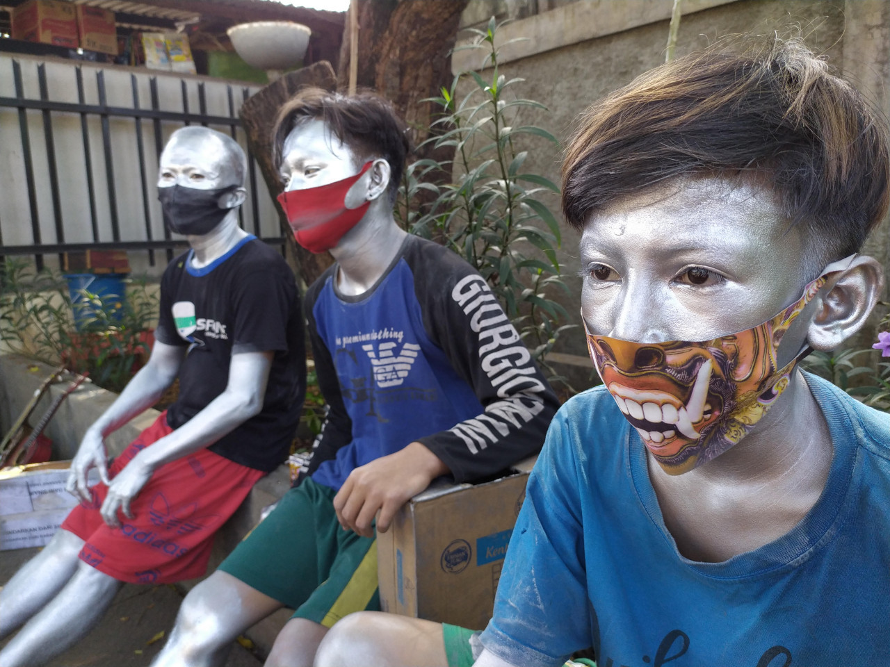 Street buskers covered in silver paint metallic take a break on July 17, 2020 along Jl. Raya Bogor in Ciracas, East Jakarta.