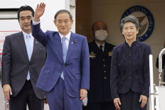 Japan's Prime Minister Yoshihide Suga waves next to his wife Mariko as he leaves for his first official overseas visit as PM, to Vietnam and Indonesia, at Haneda International Airport in Tokyo, Japan Oct.18 