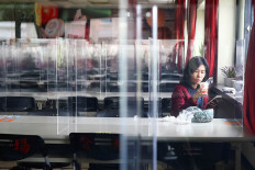 A woman sits at a table with plastic partitions as a prevention measure for the coronavirus disease (COVID-19) at a canteen of Foxconn office building in Taipei, Taiwan November 12, 2020. 