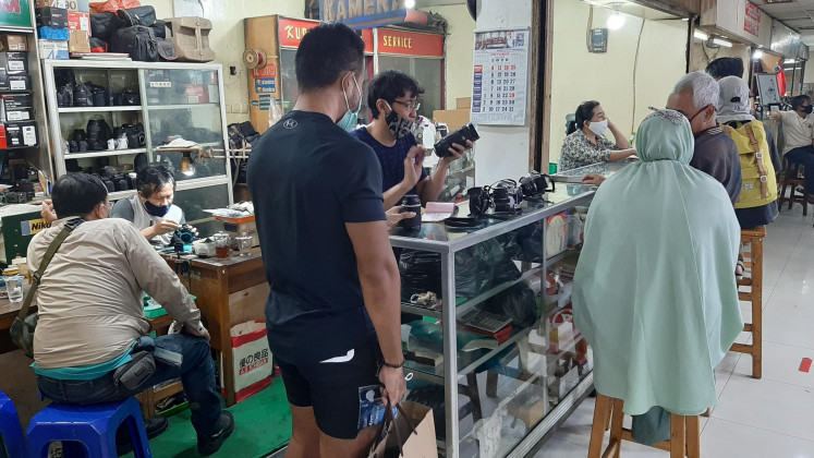 Full service: A technician in a camera shop carefully checks a customer’s camera. Apart from camera sales, the shop also offers repair services.