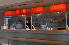 Hotel employees wearing face masks stand behind screen protections at the reception of the Rome's Sheraton Parco de Medici hotel on November 9, 2020. 