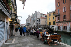 People sit at tables along the canal, as the number of people infected by the coronavirus disease (COVID-19) continues to rise, in Venice, Italy, November 14, 2020. 
