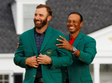 Dustin Johnson of the US is presented with the green jacket by Tiger Woods of the US after winning The Masters at the Augusta National Golf Golf, Augusta, Georgia on Sunday.