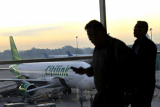Passengers walk past a Citilink airplane in Kualanamu International Airport (KNIA), Deli Serdang, North Sumatra, on June 11, 2015.