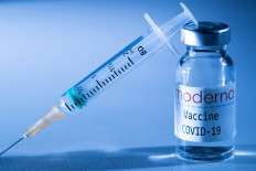 This creative image taken in a studio in Paris on November 16, 2020, showing a syringe and a vaccine vial with the reproducted logo of a US biotech firm Moderna, illustrates the announcement of an experimental vaccine against COVID-19 from Moderna that would be nearly 95% effective.