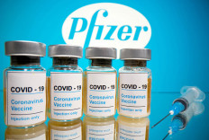 Vials with a sticker reading, 'COVID-19/Coronavirus vaccine/Injection only' and a medical syringe are seen in front of a displayed Pfizer logo in this illustration taken October 31, 2020. 