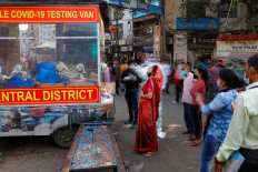 A healthcare worker wearing personal protective equipment (PPE) collects a swab sample from a woman amidst the spread of the coronavirus disease (COVID-19), at a wholesale market, in the old quarters of Delhi, India, November 17, 2020. Picture taken with slow shutter speed. 