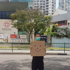 Jolovan Wham wears a mask and holds a cardboard with a drawing of a smiley face in Singapore, March 28. (Reuters/epost-robot).
Usage: 0