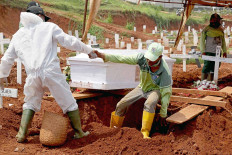 A grave worker helps his colleague out of the grave of a COVID-19 patient at Pondok Ranggon public cemetery in East Jakarta on Wednesday, Nov 12 The men had to widen the hole to make room for the coffin. JP/P.J.Leo