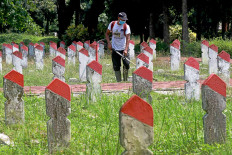 lham, 39, a caretaker at the Pahlawan Seribu Heroes Cemetery in South Tangerang, Banten, cuts weed around gravestones on Monday, Nov 9. Unlike previous years, the cemetery was closed during National Heroes Day on Nov. 10 due to the COVID-19 crisis. JP/Dhoni Setiawan.