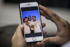 This picture taken on November 22, 2020 in Cairo shows a man holding a phone showing a picture of Egypt's self-proclaimed 'superstar' Mohamed Ramadan posted by the official Facebook page of the State of Israel in Arabic (linked to the foreign ministry) depicting Ramadan (center) hugging Israeli singer Omer Adam (left) on a Dubai rooftop. 