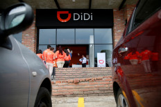 The logo of Chinese ride-hailing firm Didi Chuxing is seen as employees stand outside the drivers center in Toluca, Mexico, on April 23, 2018.