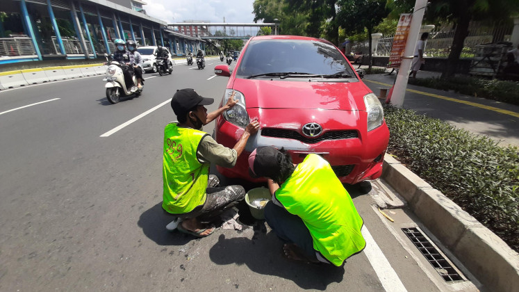 Street painters: Madi (left), assisted by his coworker, carries out polishing work on a damaged car by the roadside.