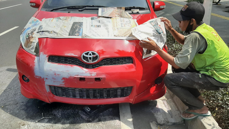 Meticulous: Newspaper is applied to protect the hood of the car from being splattered with paint.