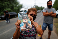 A woman holds a book "Yo soy el Diego" (I am the Diego) outside the house where Diego Maradona was staying, in Tigre, on the outskirt of Buenos Aires, Argentina on Wednesday.