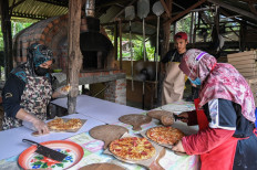 This picture taken on November 5, 2020 shows workers preparing pizzas for their lunch at the Jemapoh Pizza Kayu Api restaurant -- started by a Malaysian family to make ends meet during the economic downturn due to the COVID-19 pandemic -- in Jemapoh, in Malaysia’s Negeri Sembilan state.