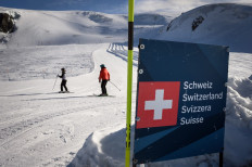 Skiers are seen behind a banner showing Swiss border above the ski resort of Zermatt in the Swiss Alps on November 28, 2020. 